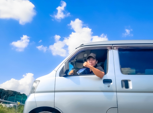 軽バンの運転席から笑顔を見せるドライバー