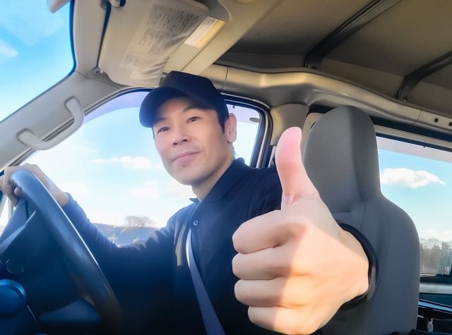 運転席でグッドサインをするドライバー