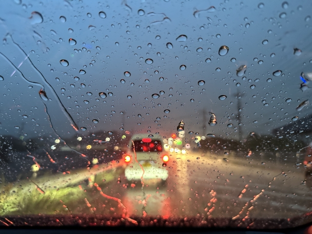 雨粒のついたフロントガラス越しの道路